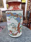 A JAPANESE IMARI CYLINDER FORM VASE, POLYCHROME LANDSCAPE PANEL WITH BROCADE SURROUND. 46CM HIGH