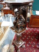 A VICTORIAN CARVED WALNUT STAND, THE TOP SECTION WITH A MONK SEATED BELOW A CANOPY SUPPORTED BY A