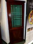 A 19TH.C.MAHOGANY FLOOR STANDING CORNER CABINET WITH GLAZED PANEL DOOR OVER FLAME MAHOGANY CUPBOARD.