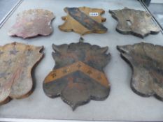 SIX EARLY CARVED AND POLYCHROME ARMORIAL SHIELD FORM CRESTS.