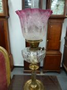 A VICTORIAN OIL LAMP WITH BRASS AND PLATED COLUMN, GLASS RESERVOIR AND ETCHED CRANBERRY TINTED SHADE