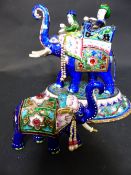 TWO INDIAN ENAMELLED SILVER COLOURED METAL FIGURES OF ELEPHANTS, THE LARGER WITH HOWDAH AND TWO