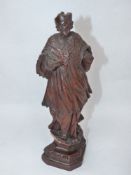 A CONTINENTAL CARVED FIGURE OF A CLERIC IN FLOWING ROBES STANDING ON A SHAPED PLINTH. H.27cms.