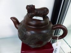 A CHINESE POTTERY TEAPOT AND COVER WITH DRAGON DECORATION. IMPRESSED MARKS TO BASE