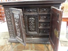 A CARVED BAROQUE STYLE MULTI DRAWER PANELLED DOOR TABLE CABINET WITH SCROLL AND FOLIATE
