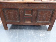 AN EARLY CARVED OAK COFFER WITH THREE PANEL TOP. W.129cms.