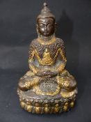 AN EASTERN PATINATED AND GILT BRONZE SEATED FIGURE OF A DEITY ON A LOTUS FORM BASE. 14CM HIGH
