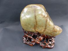 A CHINESE CARVED AND POLISHED JADE SCHOLAR'S STONE WITH CONFORMING HARDWOOD BASE. STONE. 19CM WIDE