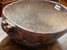 AN EARLY CARVED OVAL DEEP TREEN BOWL, THE ENDS WITH FOLIATE SCROLLS AND PROJECTING HANDLES W.46cms.