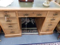 AN EDWARDIAN PALE OAK PEDESTAL DESK WITH GREEN LEATHER WRITING SURFACE.