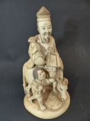 A JAPANESE CARVED IVORY OKIMONO OF A SAGE ASTRIDE A BULLOCK WITH ATTENDANT. RED INSET TABLET TO BASE