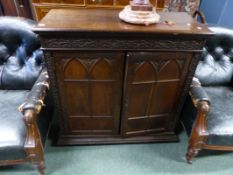 A VICTORIAN GOTHIC REVIVAL OAK SIDE CUPBOARD WITH TWIN ARCH PANEL DOORS.