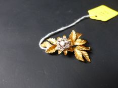 A gold coloured precious metal flower brooch set with a cluster of twelve small diamonds.