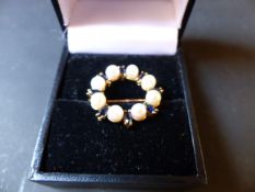 A 9ct gold coloured seed pearl and sapphire set circle brooch.