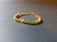 A 14ct gold emerald set tennis bracelet set with diamond crosses.