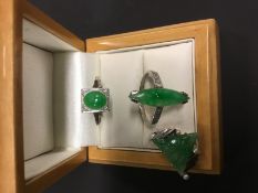 An 18ct and platinum set oval jade dress ring, another similar and a jade set C brooch (3).