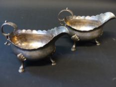 A pair of George III silver sauce boats with frilled rims on hoof feet. London 1771. Makers initials