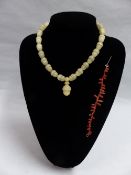 AN ALABASTER NECKLACE OF STYLIZED ACORN DESIGN WITH A CORAL BRACELET