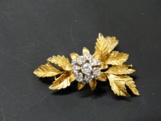 A GOLD COLOURED PRECIOUS METAL DIAMOND SET FLOWER BROOCH. 5CM LONG