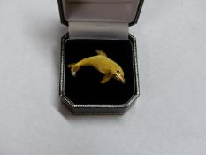 A 18K DOLPHIN SHAPED BROOCH WITH RUBY SET EYE. APPROXIMATELY 7.5 GRAMS. DIAMOND SINGLE STONE 4CM