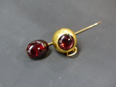 A PRECIOUS METAL MEMORIAL ORB PENDANT SET WITH A GARNET AND INSET HAIR TO REVERSE. BY JOHN