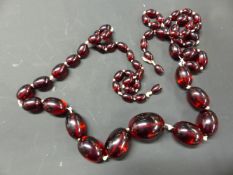 A GRADUATED RED AMBER NECKLACE. 112CM LONG