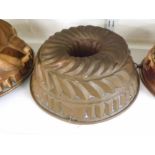 A VINTAGE COPPER JELLY MOULD OF SWIRLED CIRCULAR FORM WITH OPEN CENTRE, (WORN), 10" DIAMETER AND 4