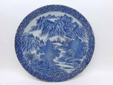 A CHINESE CIRCULAR PLATE PRINTED IN BLUE WITH A RIVER SCENE, 12 1/4" DIAMETER