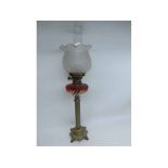 A 19TH CENTURY OIL LAMP WITH CLEAR GLASS CHIMNEY, FROSTED FRILLED GLASS SHADE, RIBBED RED TINTED