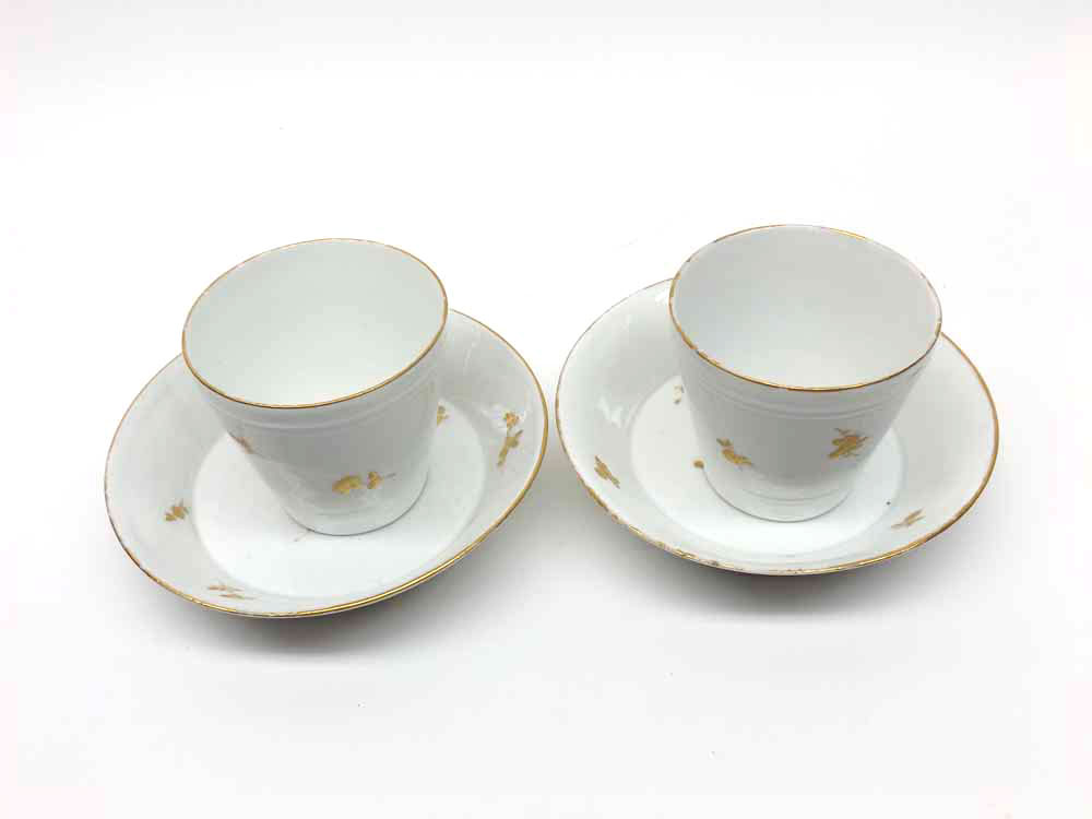 Pair of 19th century continental coffee cans and saucers, decorated with gold sprays on a pale