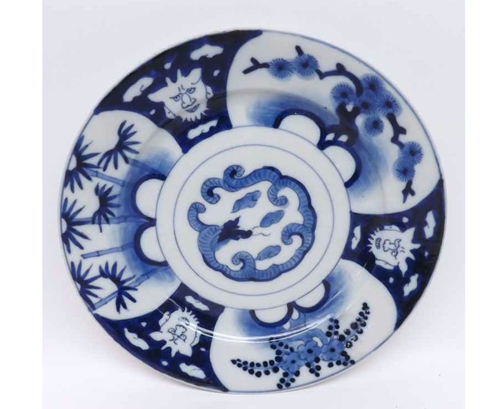 Oriental circular plate, painted in underglaze blue with compartmentalised design of grotesque masks