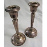 Pair of George V candlesticks with fixed nozzles and urn shaped sconces on tapering and faceted