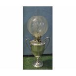 Unusual oil lamp with clear glass chimney, frosted glass shade, over a silver plated trophy-style