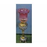 Ornate oil lamp, fitted with clear glass chimney, cranberry frilled glass shade, raised on a