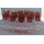 Set of seventeen large wines, with cranberry and gilt highlighted bowls, raised on clear stems and