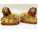 Pair of rust coloured models of reclining lions, with composition eyes, a further large model of a