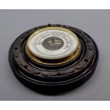 Small late 19th or early 20th century aneroid barometer in carved dark wood circular frame