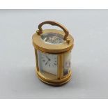 Small 20th century oval shaped carriage clock, sides with ceramic panels decorated with cherubs, the