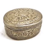 A small oval white metal Pill Box, the pull-off lid and body decorated with scrolled foliate detail,