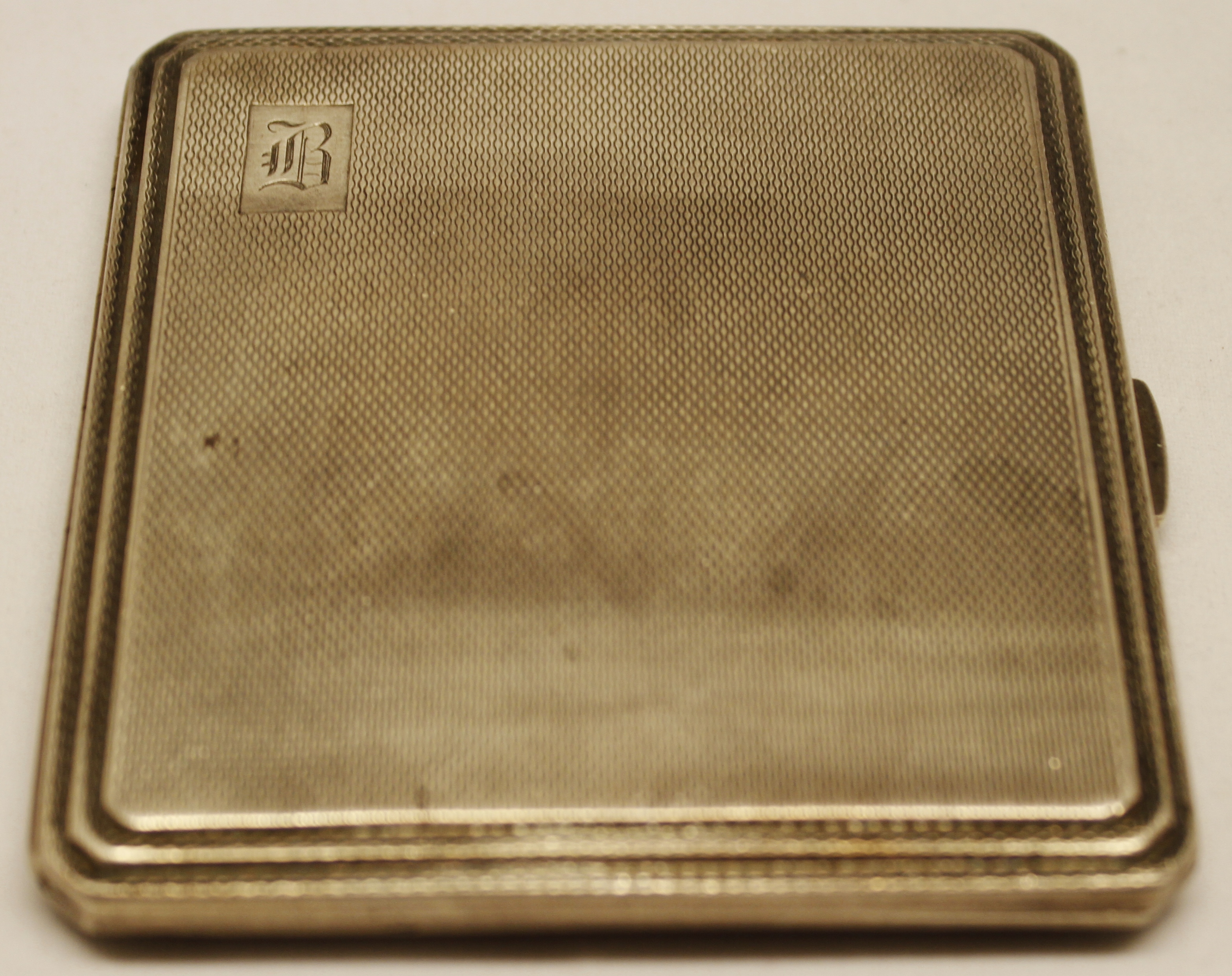 George VI cigarette case, of hinged square form with canted corners and all over engine-turned