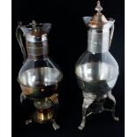 Two similar 20th Century glass mulled wine jugs with metal mounts, lids and warming stand bases,