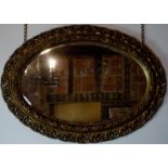 Early 20th Century carved gilt gesso framed oval wall mirror in Rococo style, having pierced