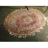Chinese pink ground and floral bordered oval thick pile wool carpet, with tasselled edge, 60 x 36