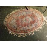 Chinese pink ground and floral bordered oval thick pile wool carpet, with tasselled edge, 60" x 36"