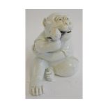 An amusing and well modelled Japanese Hirado porcelain model of a seated monkey holding a peach, his