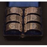 Cased set of six electro-plated napkin rings, each of circular form and modelled in the form of a