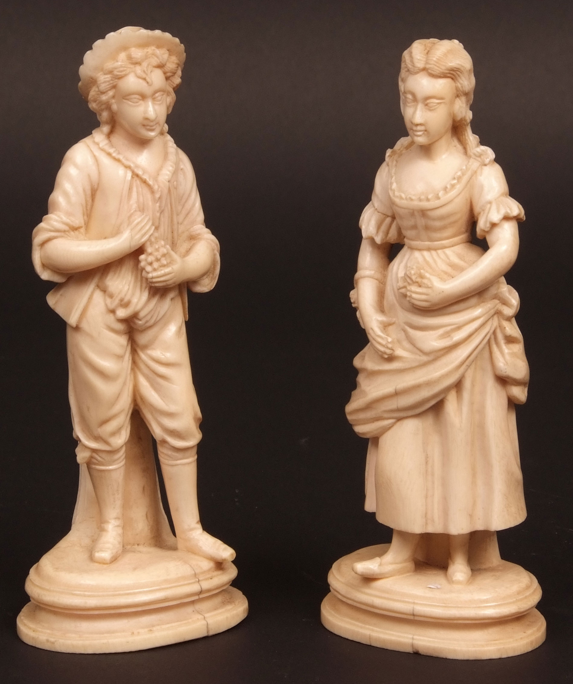 Pair of 19th century ivory carved figures of young man and woman in period costume, each clutching