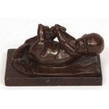 Bronze patinated spelter figure of a child lying on its back, mounted on a marble socle, 5" long