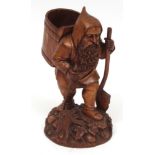 Treen carved figure of bearded man with a pannier on his back with a spade in his left hand and a