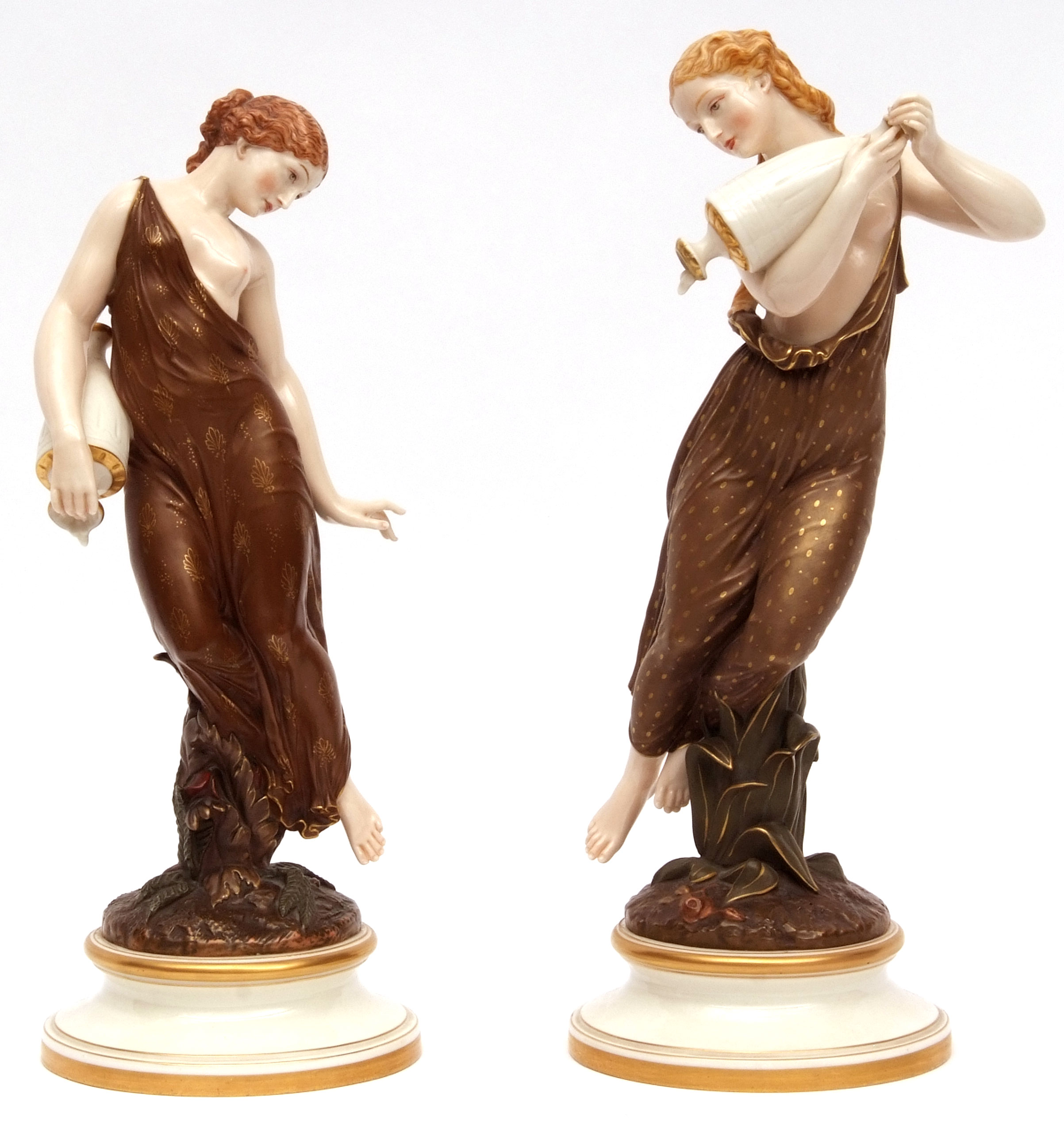 Near pair of Royal Worcester figures of maidens clutching vessels, one wearing a gilded sprig-